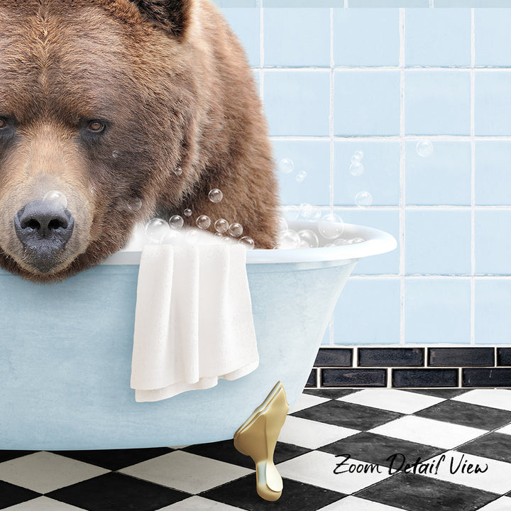 A large brown bear is sitting in a bathtub filled with bubbles, with a towel and a gold object nearby.