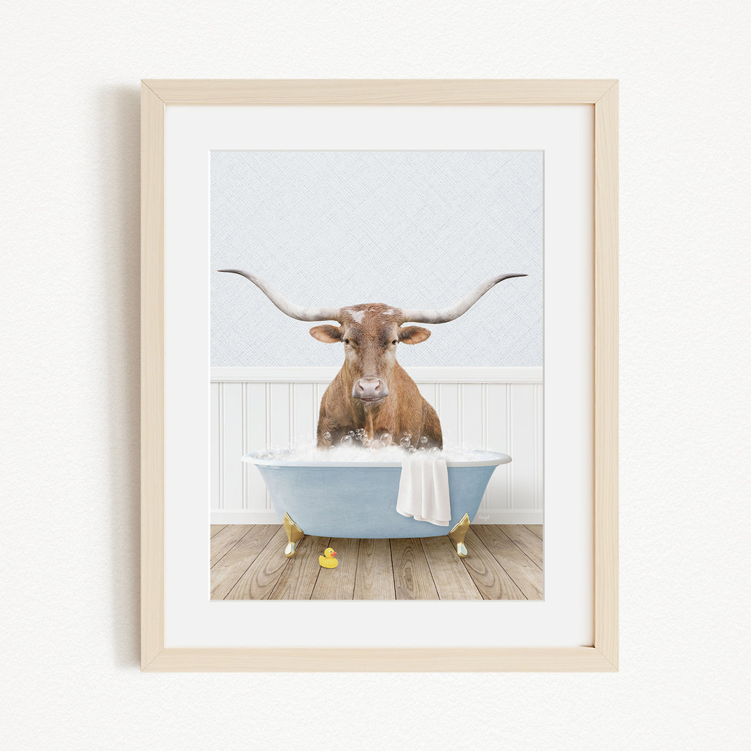 A brown cow with large horns is sitting in a blue bathtub filled with water, surrounded by yellow rubber duckies.