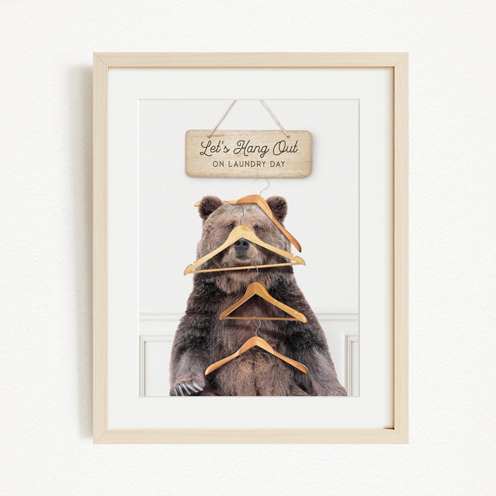 A framed image of a bear sitting in front of a sign that says "Let's Hang Out on Laundry Day".