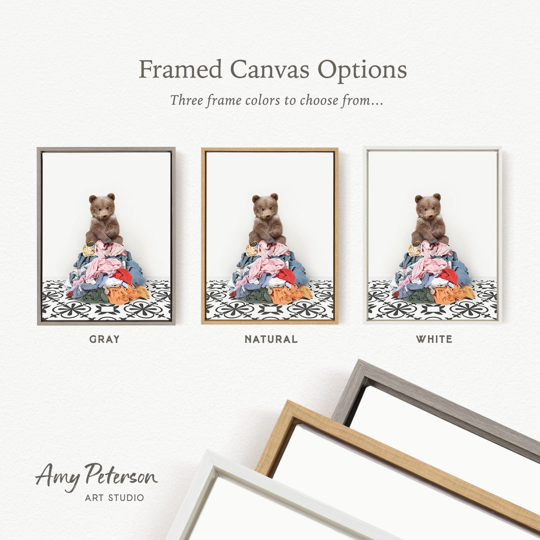 three framed canvas options, each featuring a teddy bear sitting on a pile of clothes. The options include a gray frame, a natural frame, and a white frame.