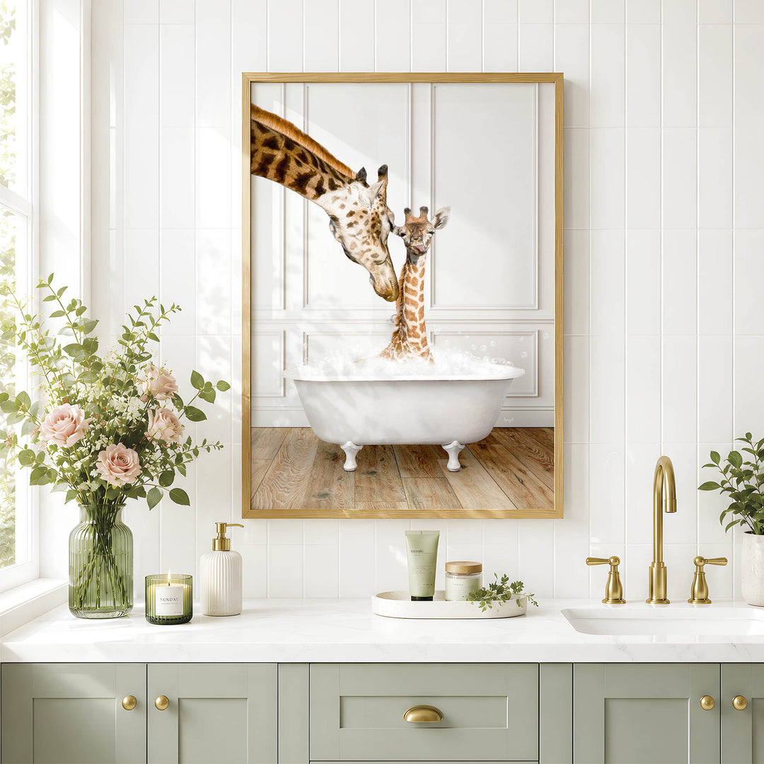 A framed image of two giraffes standing in a bathtub, with one giraffe reaching over the other, is displayed on a white wall above a bathroom counter with various toiletries and a vase of flowers.
