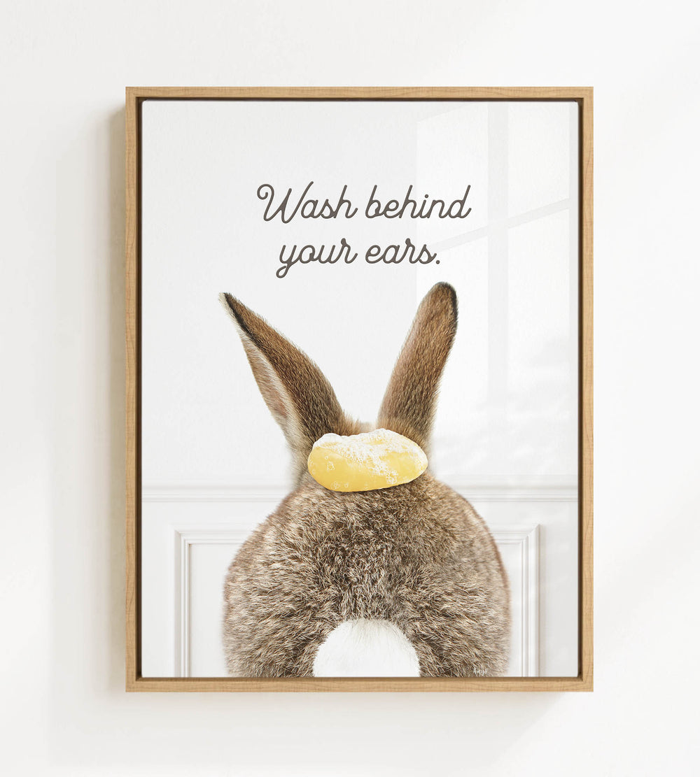 A framed image of a rabbit with a yellow object on its head, accompanied by the text "Wash behind your ears."
