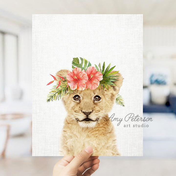 a hand holding up a card with a picture of a lion cub wearing a flower