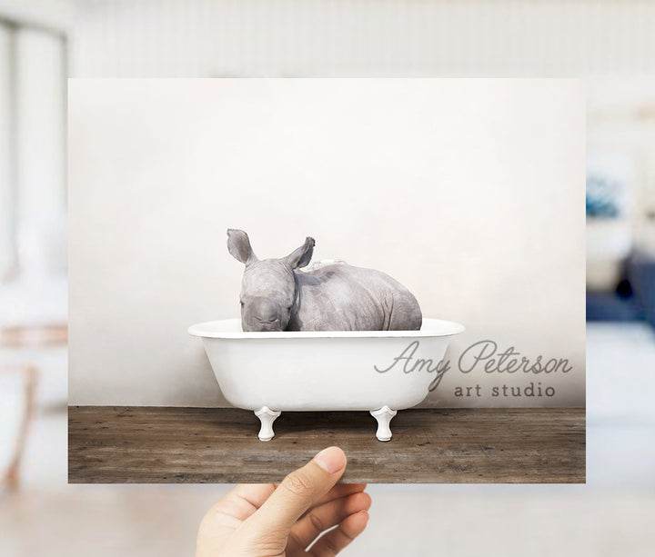 a hand holding up a card with a rhino in a bathtub