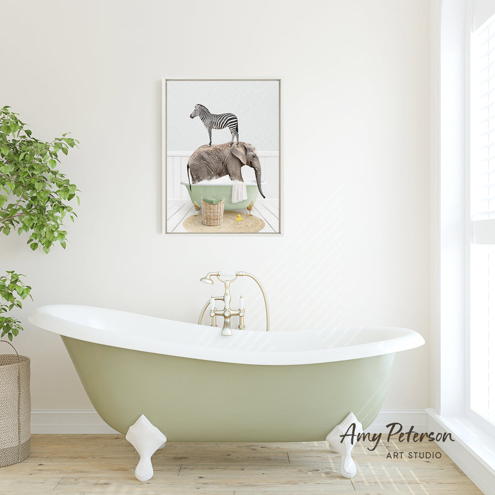 A green clawfoot bathtub with a framed image of a zebra and an elephant on the wall above it, in a bathroom setting with a potted plant to the left.