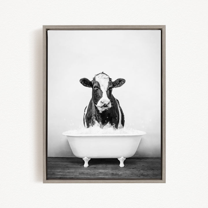 A black and white photograph of a cow standing in a bathtub filled with water.