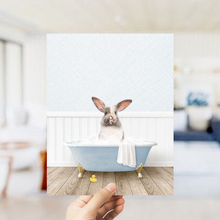 A white rabbit sitting in a blue bathtub filled with water, with a yellow rubber duck floating nearby.