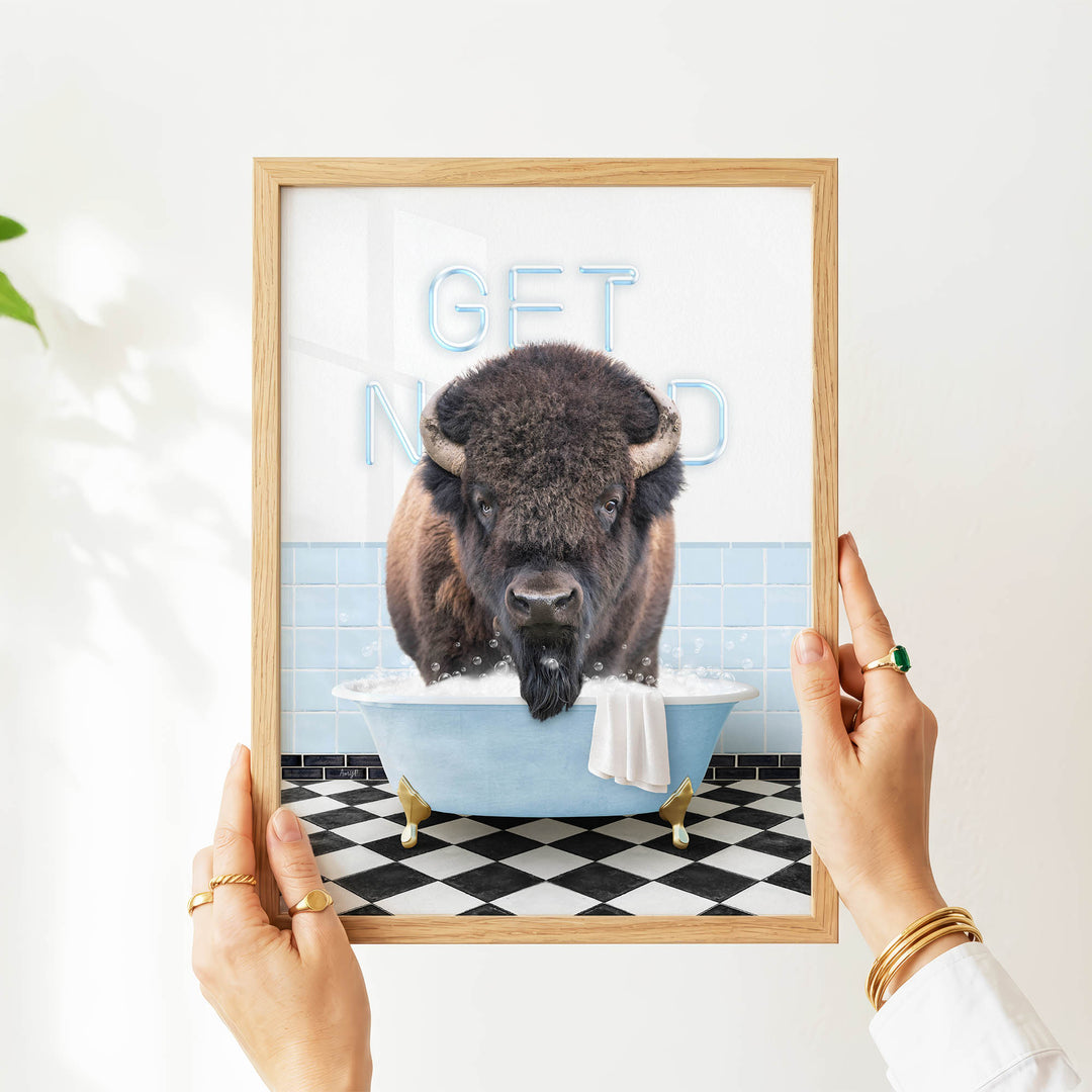 A person's hands are holding a framed image of a buffalo in a bathtub, with the text "GET NICKED" displayed on the frame.