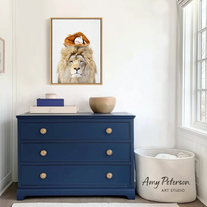 a blue dresser with a framed picture of a lion wearing a baseball cap on top of it. The dresser is situated in a room with a window and a white basket.