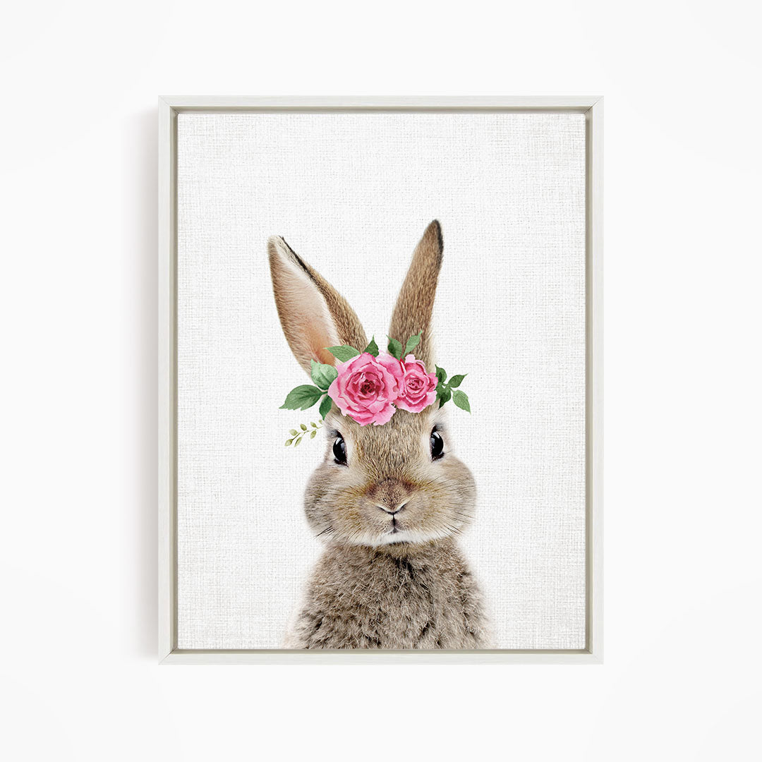 A cute bunny wearing a floral crown of pink roses and greenery.
