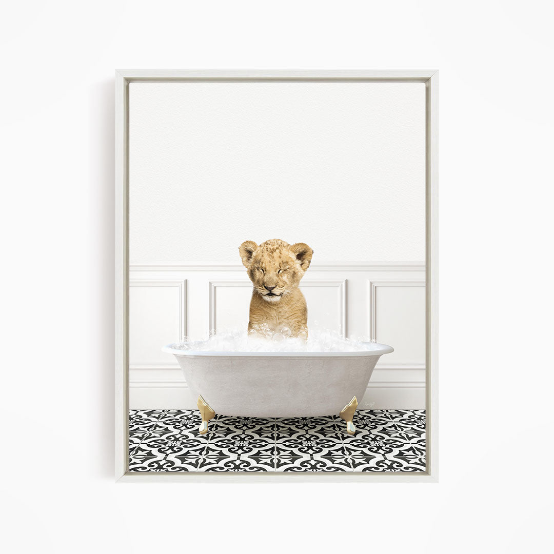 A young lion cub sitting in a white bathtub filled with water, surrounded by a black and white patterned floor.