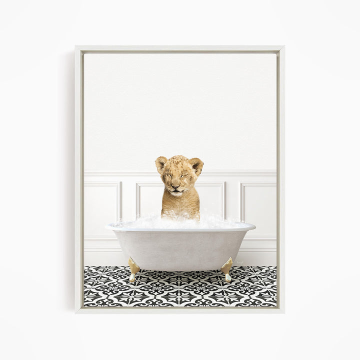 A young lion cub sitting in a white bathtub filled with water, surrounded by a black and white patterned floor.