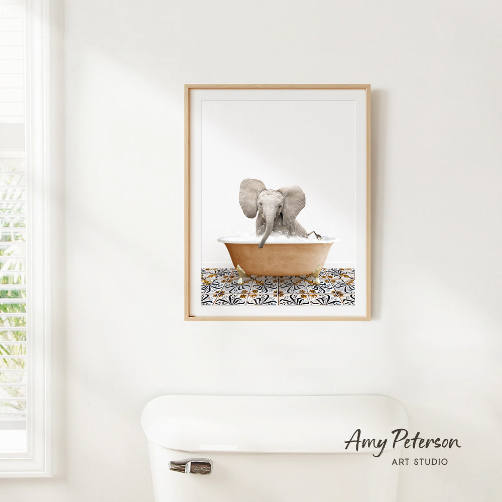 A framed image of an elephant sitting in a bathtub, with a patterned tile on the floor.