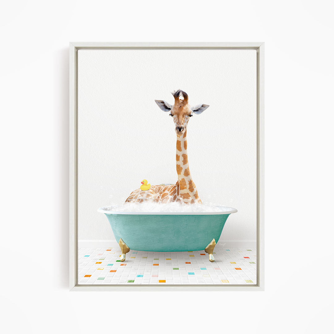 A giraffe is sitting in a green bathtub filled with bubbles, with a yellow rubber duck floating nearby.