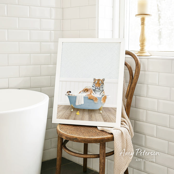 A framed image of a tiger sitting in a bathtub, surrounded by various objects, including a yellow rubber duck and a white towel.