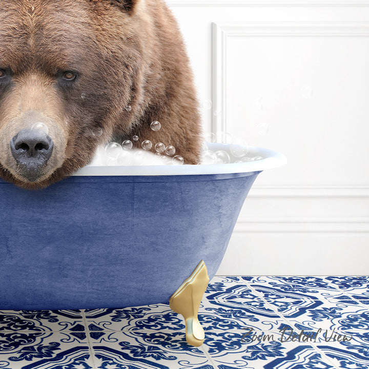 A brown bear is sitting in a blue bathtub filled with bubbles, with a gold faucet and a patterned tile floor visible in the background.