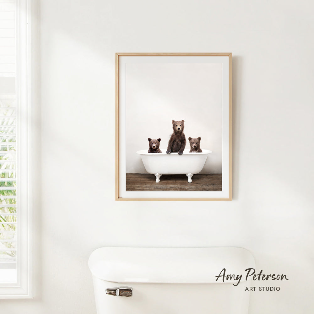 A framed photograph of three bears sitting in a bathtub, with the bears appearing to be brown and black.
