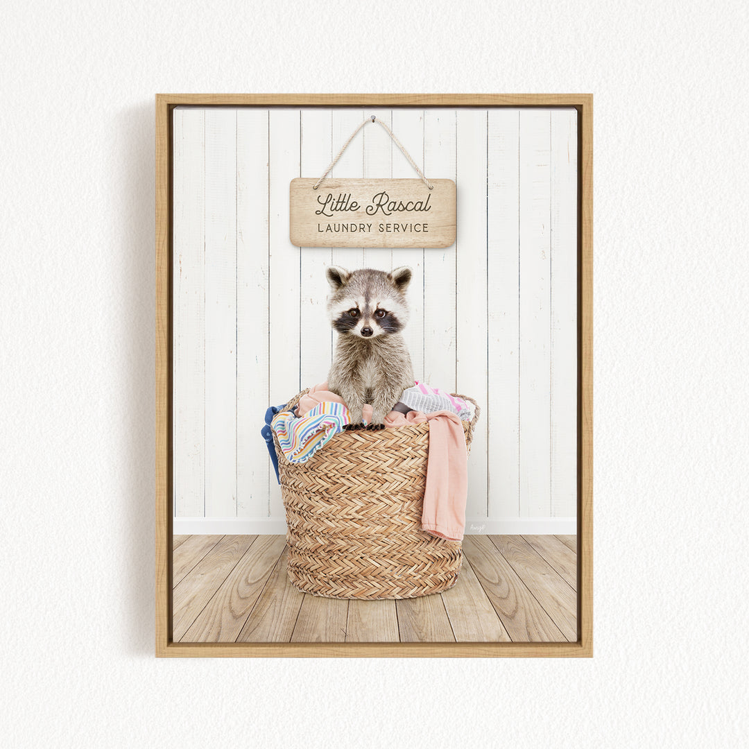 A raccoon sitting in a woven laundry basket, with a sign for "Little Racal Laundry Service" hanging above it.