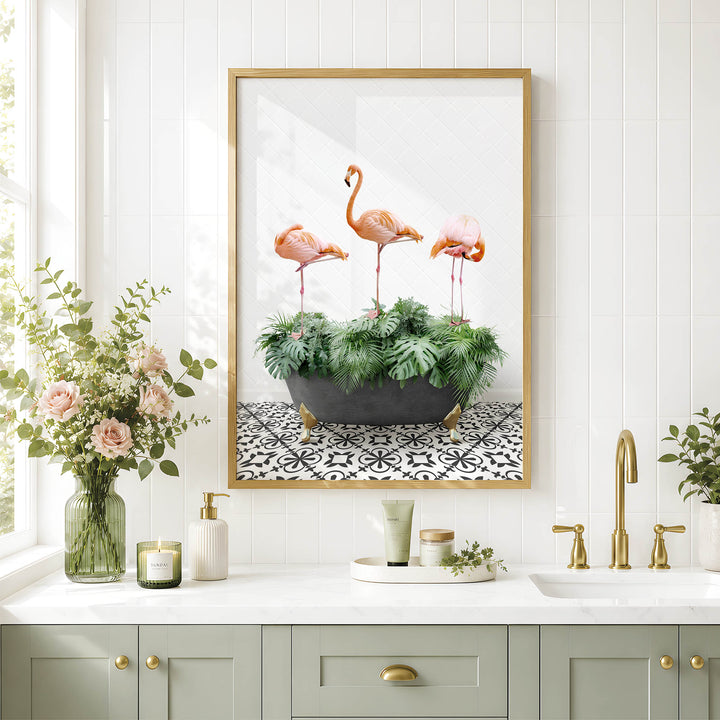 a bathroom with a framed picture of three flamingos standing on a plant in a black pot, placed above a white countertop with various toiletries and a vase of flowers.