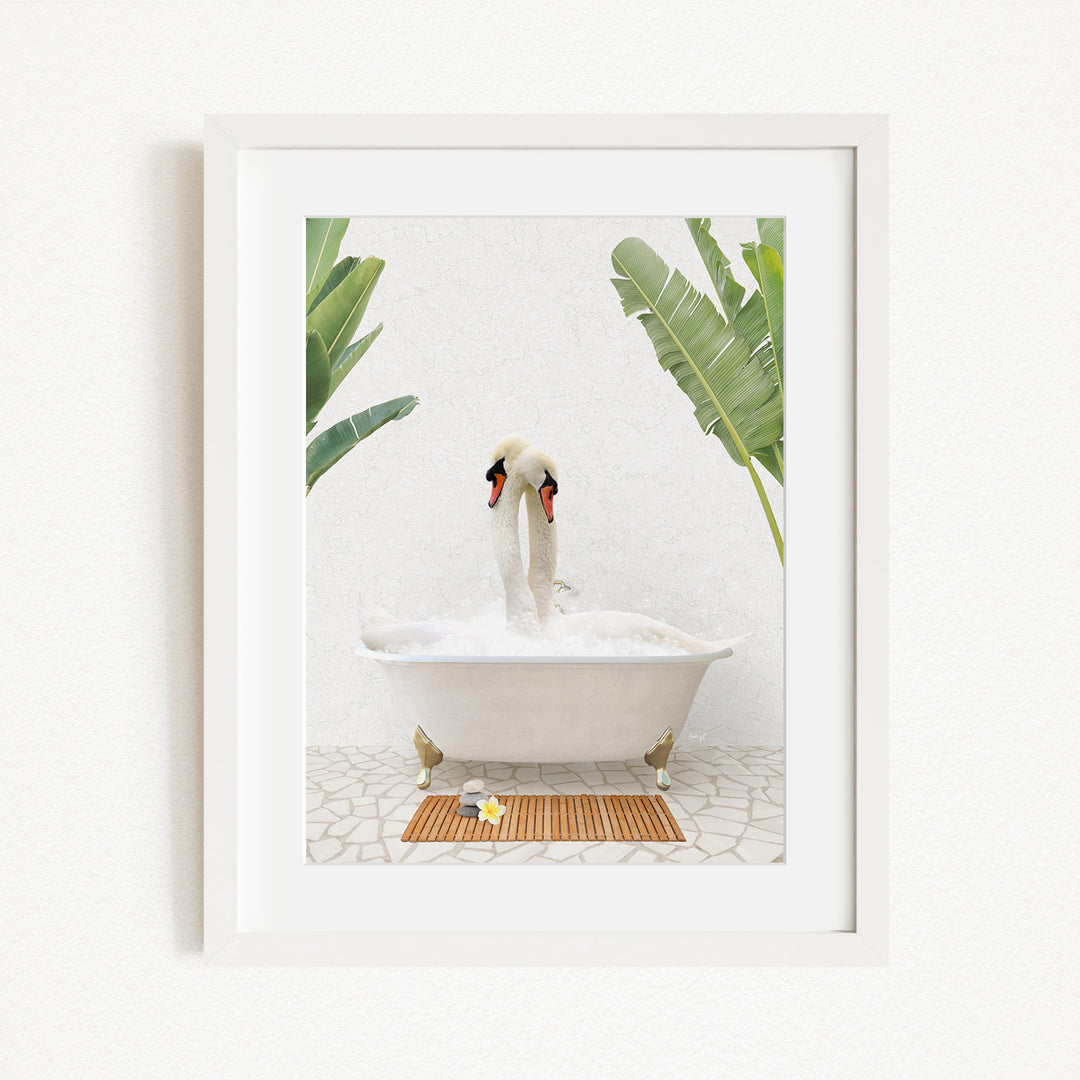 A white swan is sitting in a white bathtub filled with bubbles, surrounded by green plants and a wooden mat on the floor.