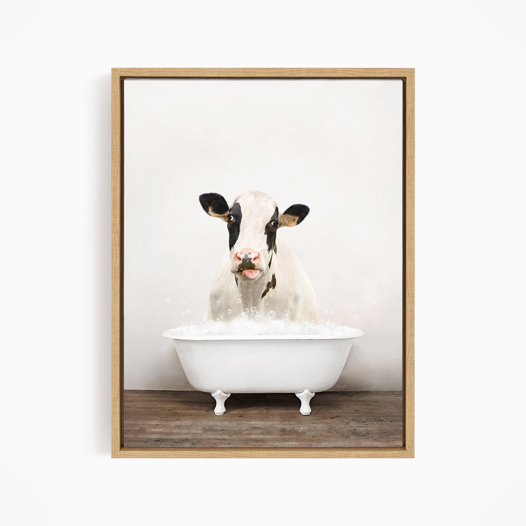 A black and white cow is sitting in a white bathtub filled with water, creating a whimsical and humorous scene.