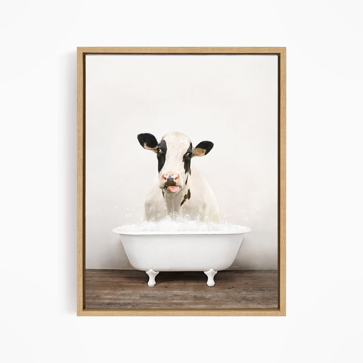 A black and white cow is sitting in a white bathtub filled with water, creating a whimsical and humorous scene.