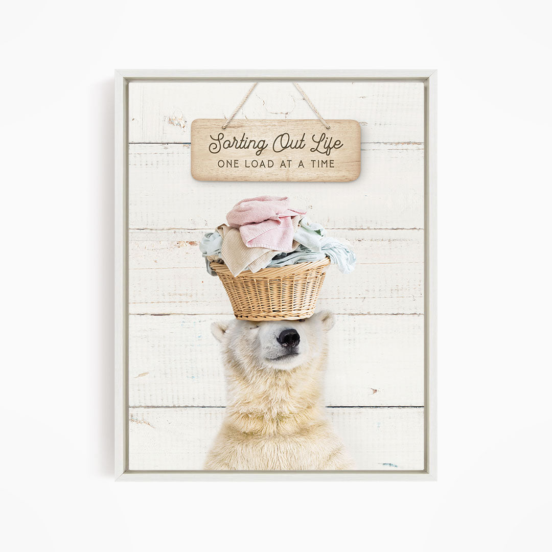 A polar bear balancing a basket of laundry on its head, with a sign above that says "Sorting Out Life One Load at a Time".