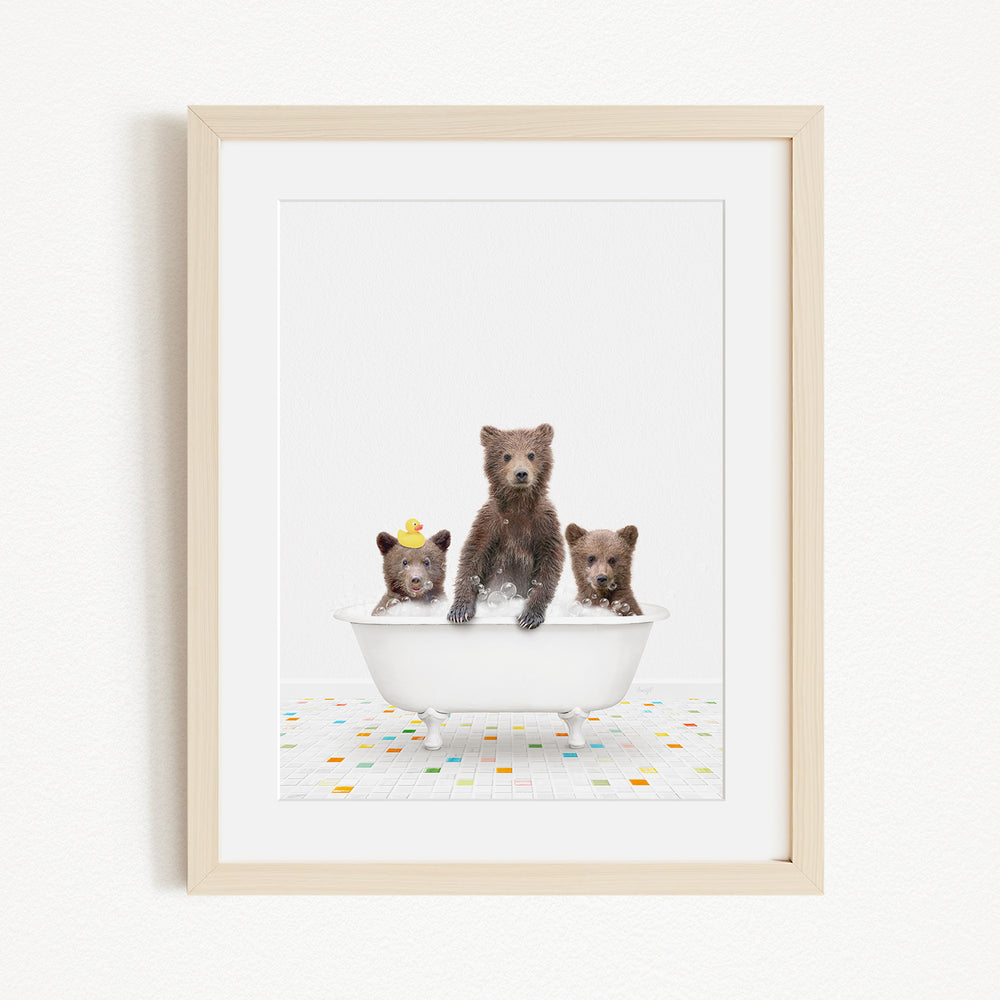 A framed image depicting three bears sitting in a white bathtub, with one bear wearing a yellow hat.