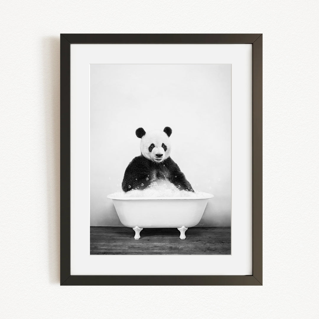 A panda bear sitting in a bathtub filled with bubbles, looking directly at the camera.