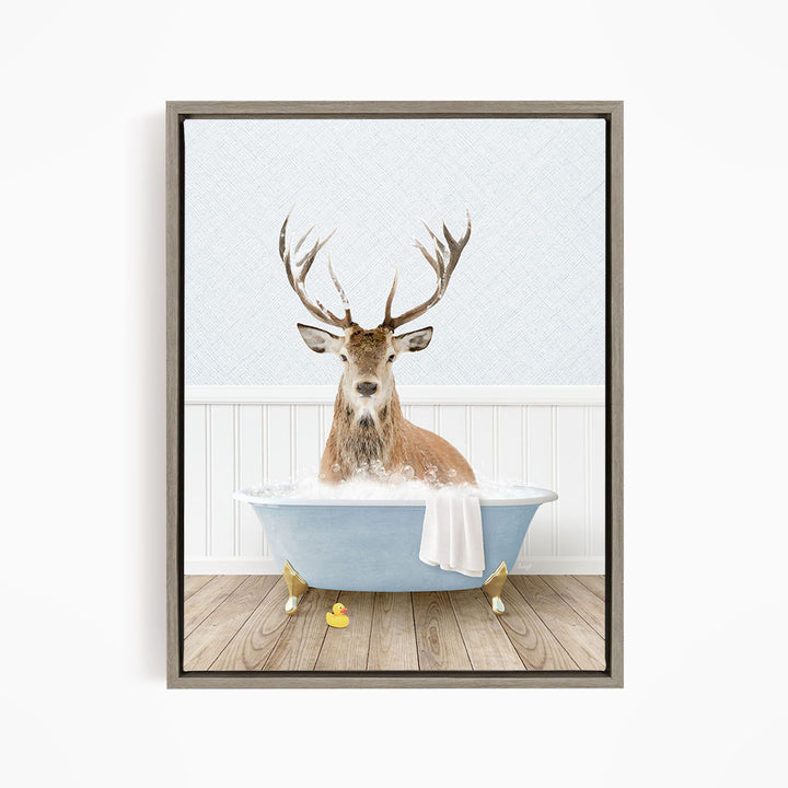 A deer with large antlers is sitting in a blue bathtub filled with water, surrounded by rubber ducks.