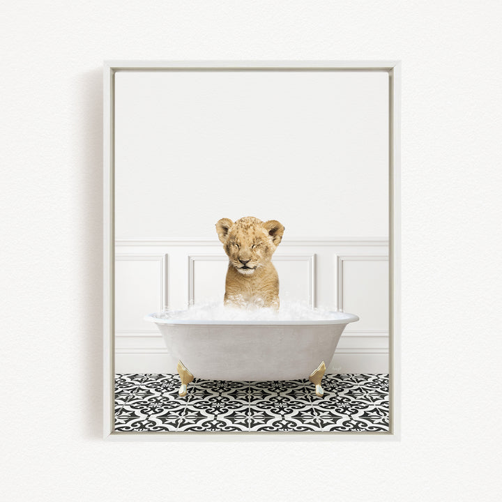 A young lion cub sitting in a white bathtub filled with water, surrounded by a black and white patterned floor.