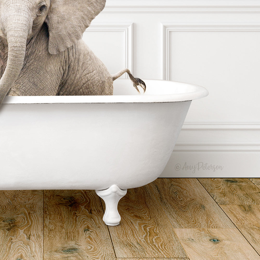 A large elephant is sitting in a white bathtub, with its trunk curled around the edge of the tub.