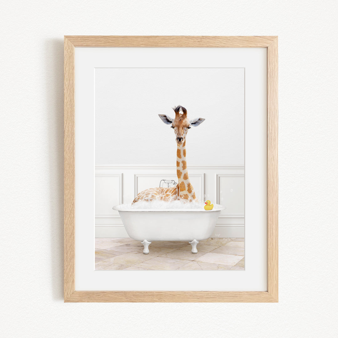 A giraffe is sitting in a white bathtub filled with water, surrounded by bubbles, with a yellow rubber duck floating nearby.