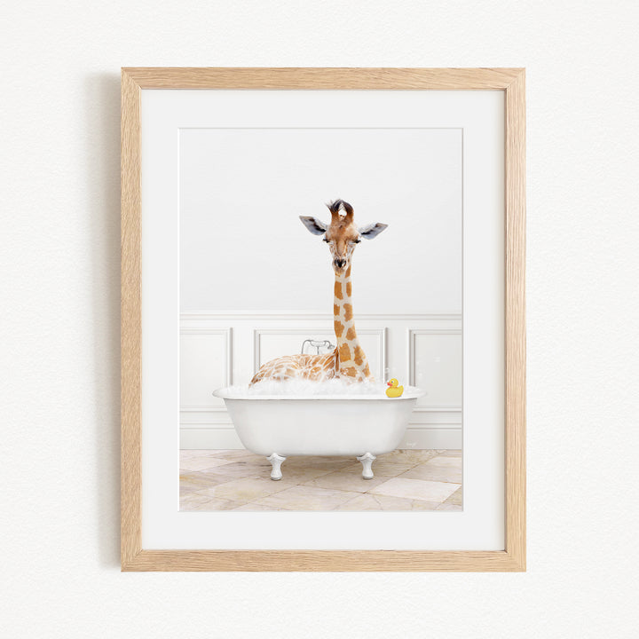 A giraffe is sitting in a white bathtub filled with water, surrounded by bubbles, with a yellow rubber duck floating nearby.