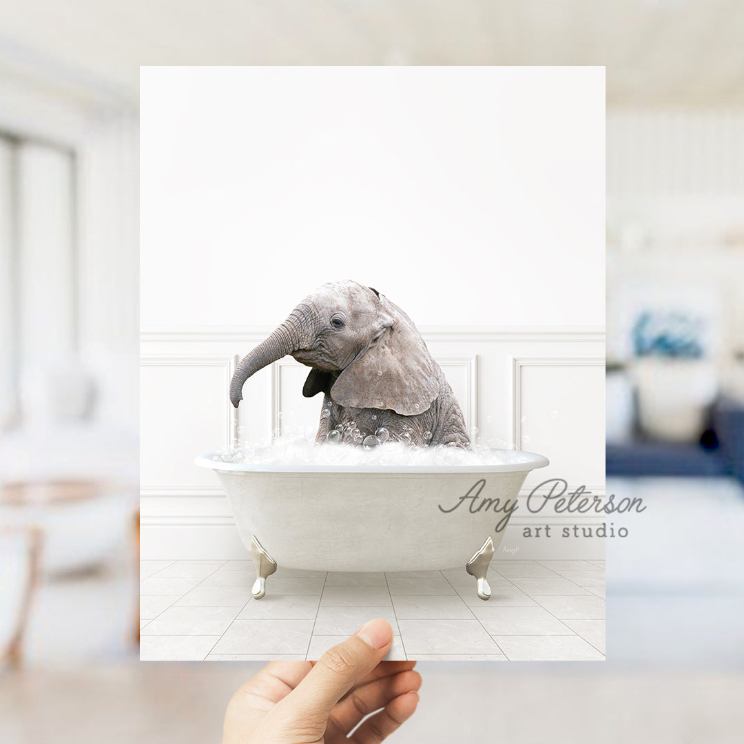 a person holding up a picture of a baby elephant in a bathtub