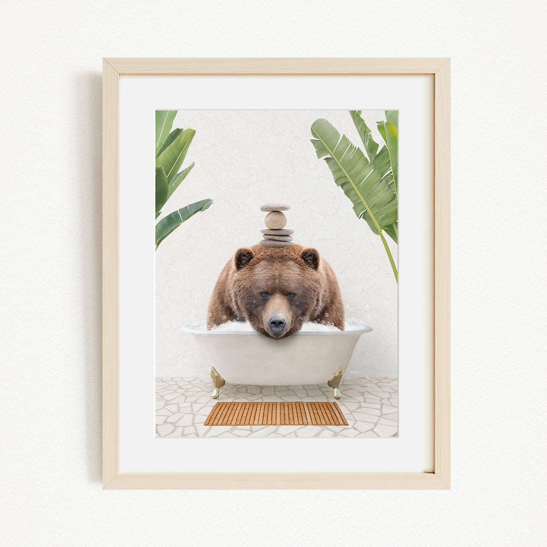 A brown bear is sitting in a white bathtub filled with water, surrounded by green plants and a wooden mat on the floor.