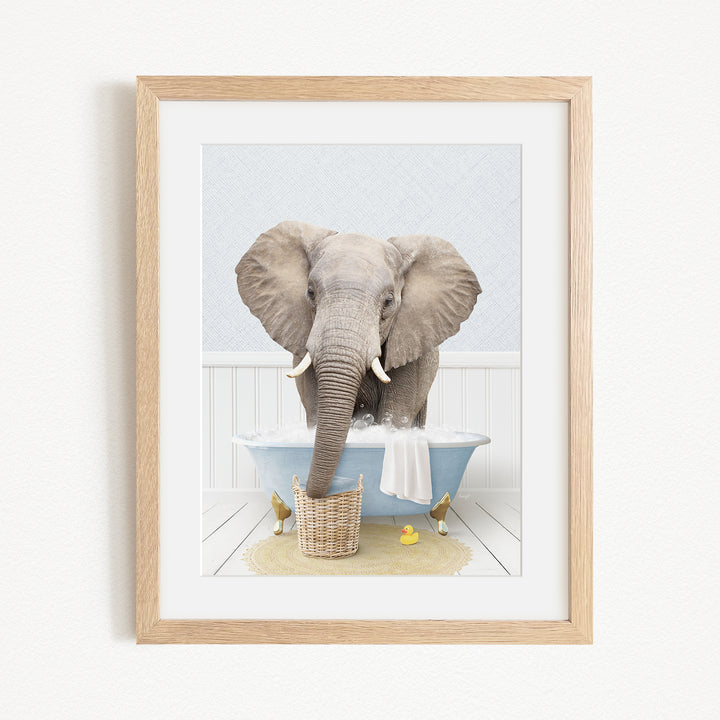 A gray elephant is sitting in a blue bathtub filled with water, surrounded by yellow rubber ducks.