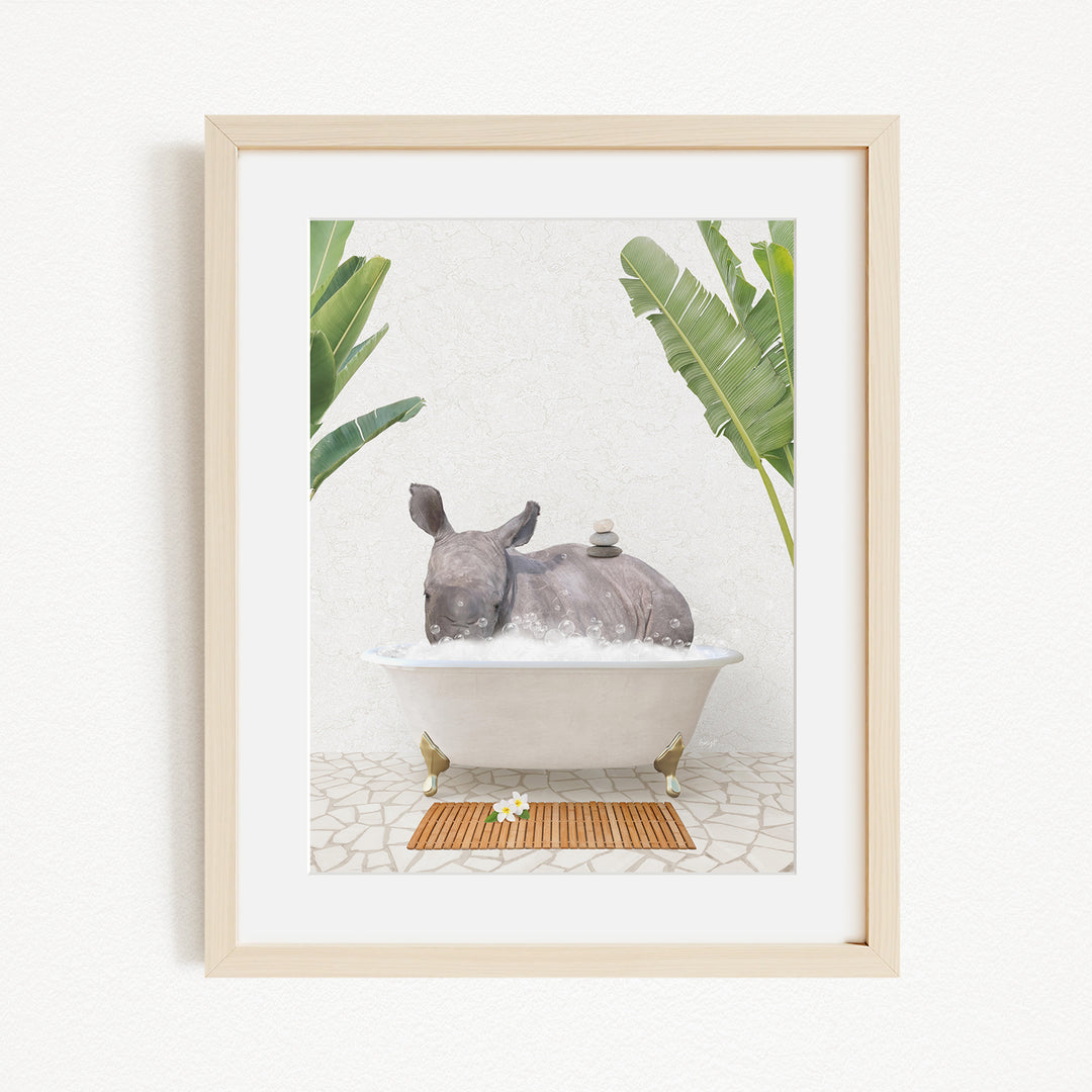 A framed image depicting a rhinoceros sitting in a bathtub filled with water, surrounded by tropical plants.
