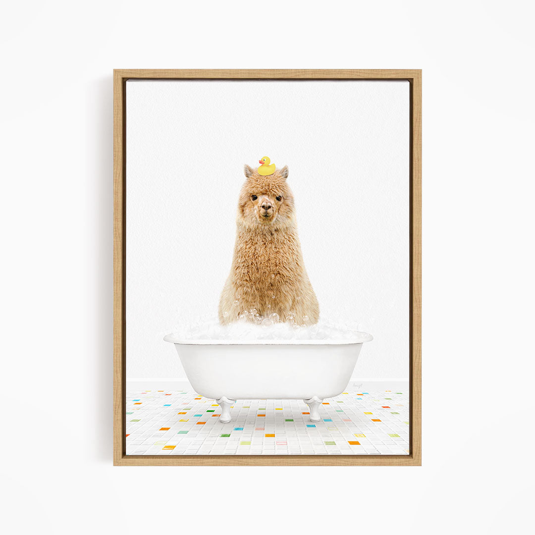 A fluffy brown llama sits in a white bathtub filled with bubbles, with a yellow rubber duck perched on its head.