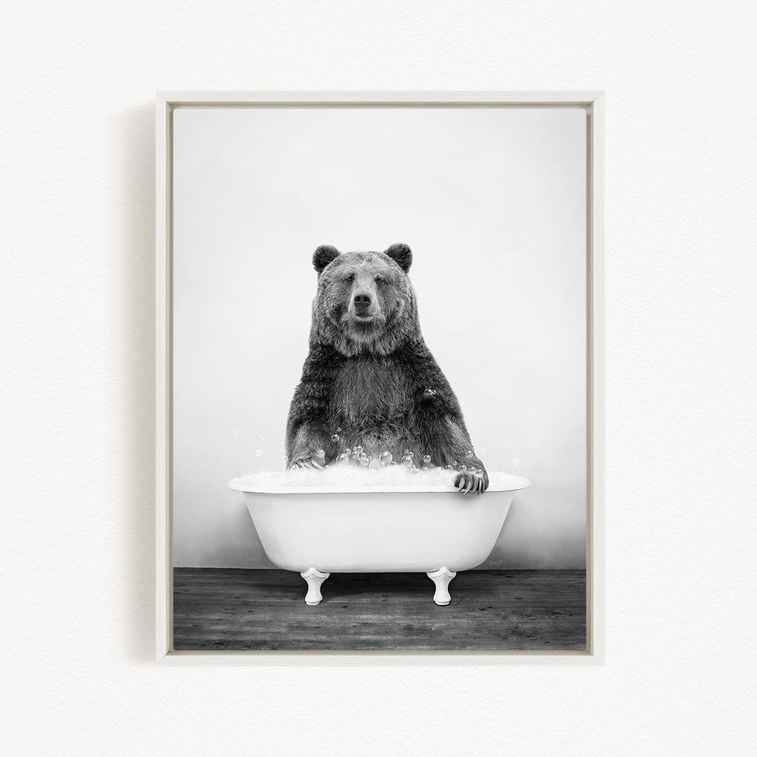A black and white image of a bear sitting in a bathtub filled with water.