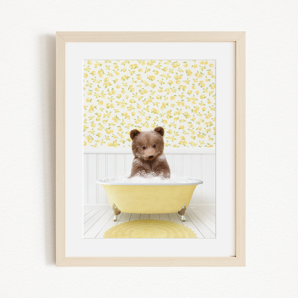 A small brown bear sitting in a yellow bathtub filled with bubbles, surrounded by a yellow floral wallpaper.