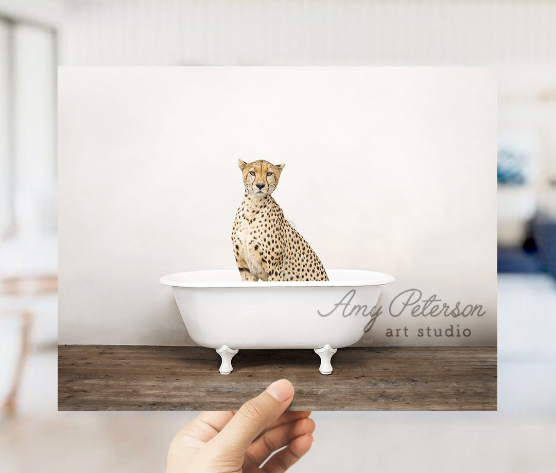 a hand holding a card with a cheetah sitting in a bathtub