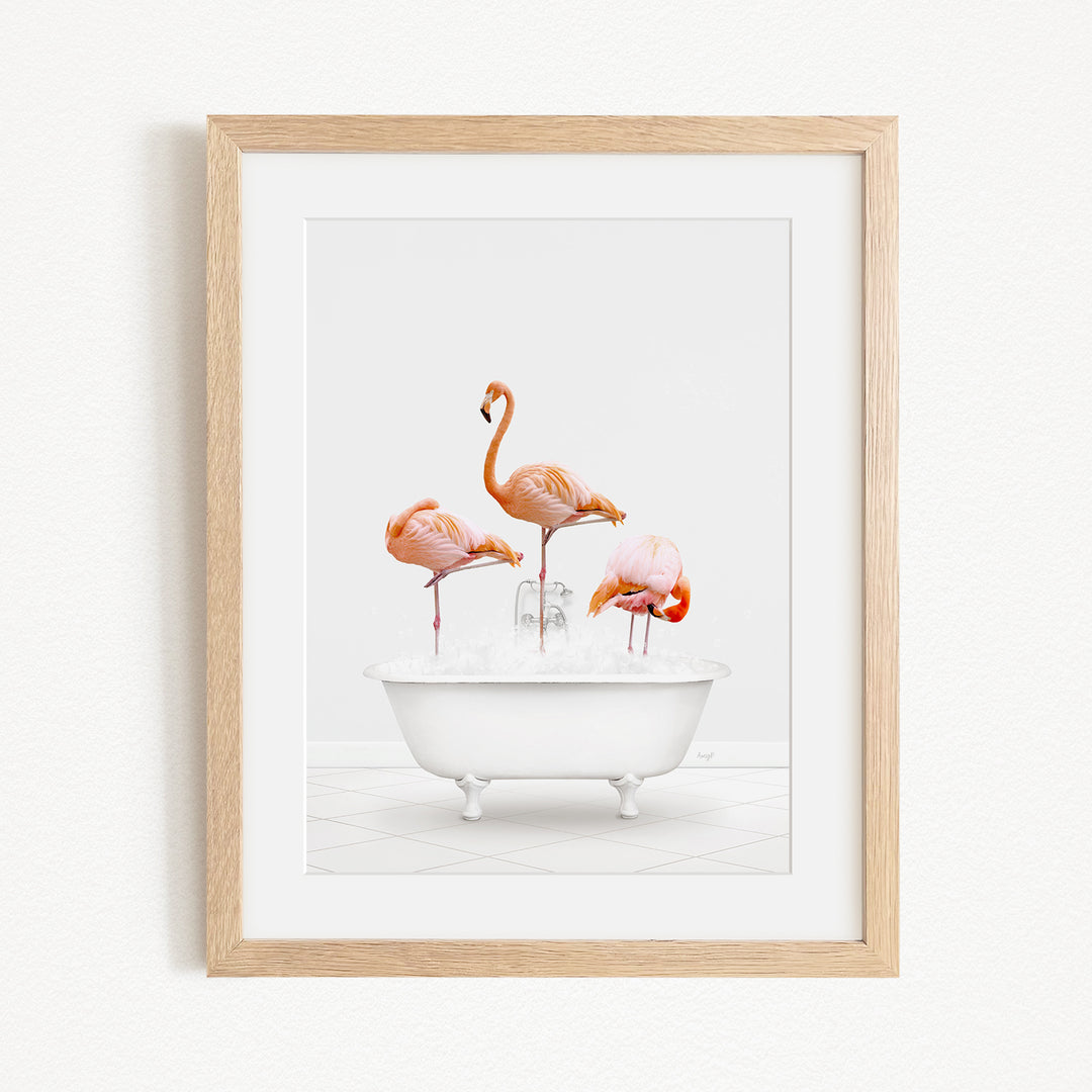 A framed image depicting three flamingos standing in a white bathtub filled with water.