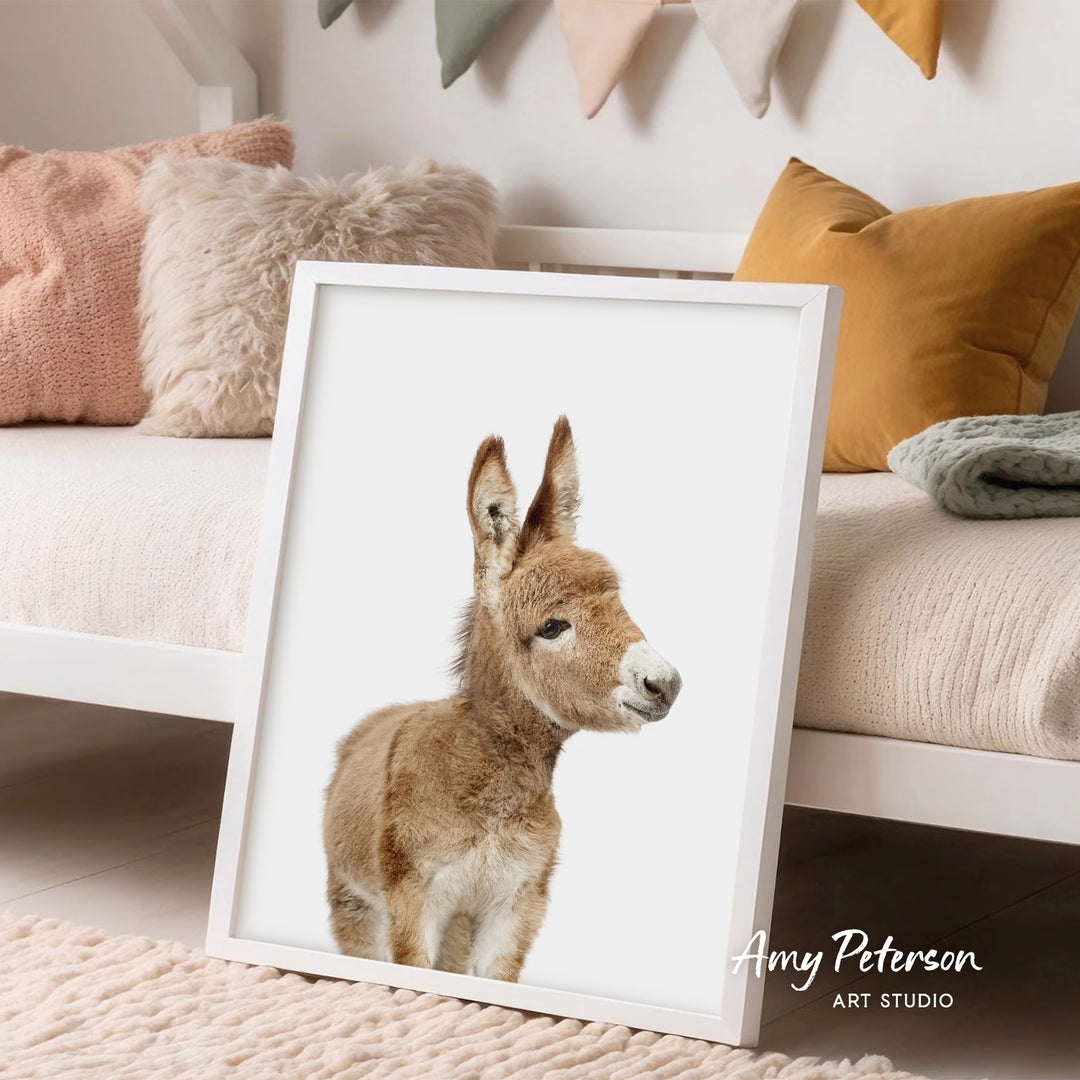 A framed image of a donkey is displayed in a cozy living room setting with pillows and blankets.