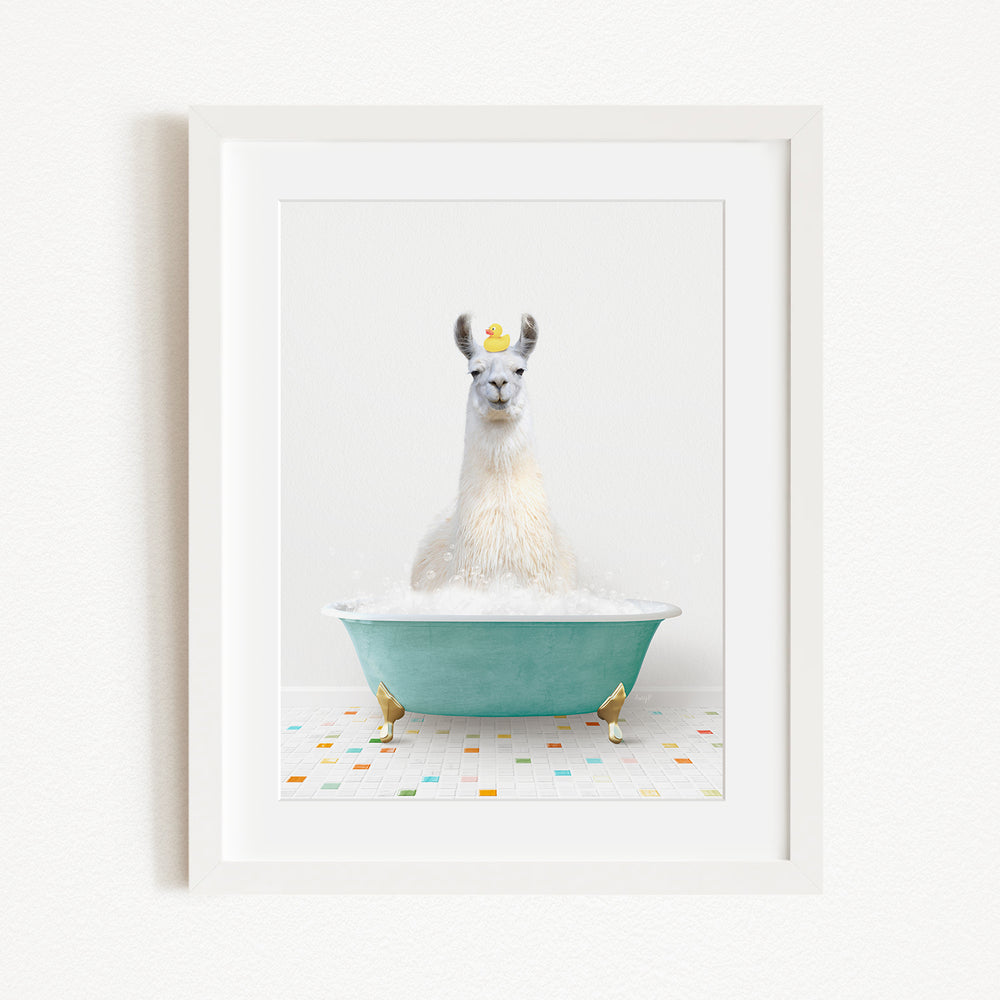 A white llama sitting in a green bathtub filled with bubbles, with a yellow rubber duck floating on the water.
