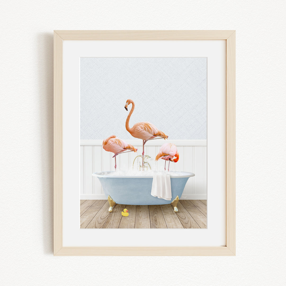 A framed image depicting three flamingos standing in a bathtub, with one flamingo standing on the edge of the tub and the other two standing inside the tub.