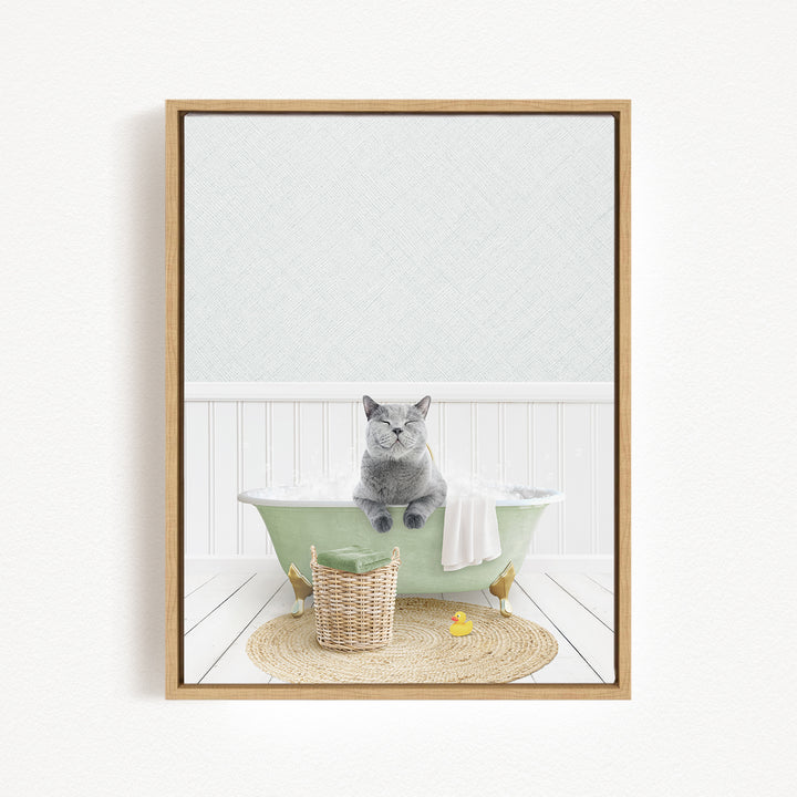 A gray cat sitting in a green bathtub filled with bubbles, surrounded by a basket of toys and a yellow rubber duck.