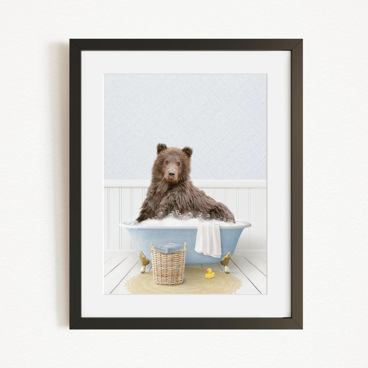 A brown bear sitting in a blue bathtub, surrounded by rubber ducks and a basket.