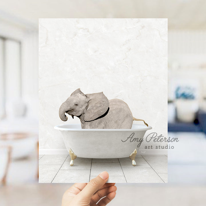 a hand holding a photo of an elephant in a bathtub