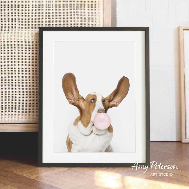 A framed photograph of a dog blowing a bubble gum bubble, with the dog's face and ears prominently featured in the center of the frame.